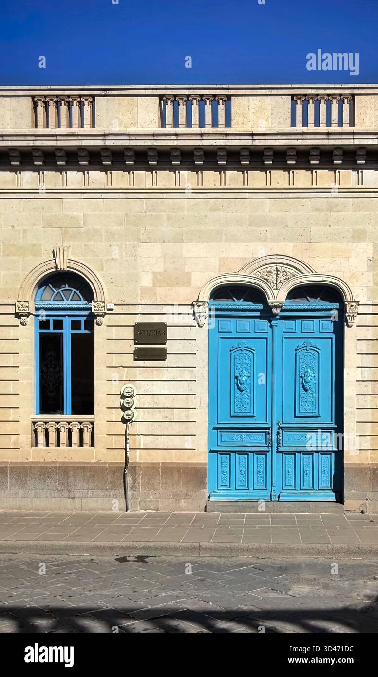 Facciata di un edificio storico con porte blu ornate e finestre ad arco in stile architettonico neoclassico sotto un cielo azzurro Foto Stock
