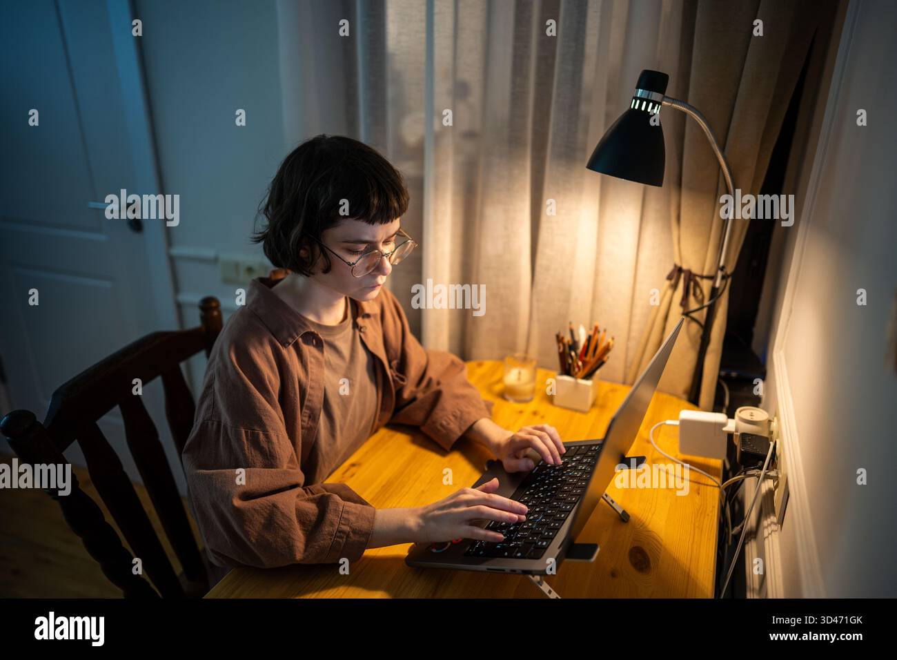 Giovane lavoratrice freelance che lavora fino a tarda notte con un notebook, finanzia i progetti, scrive i report. Foto Stock
