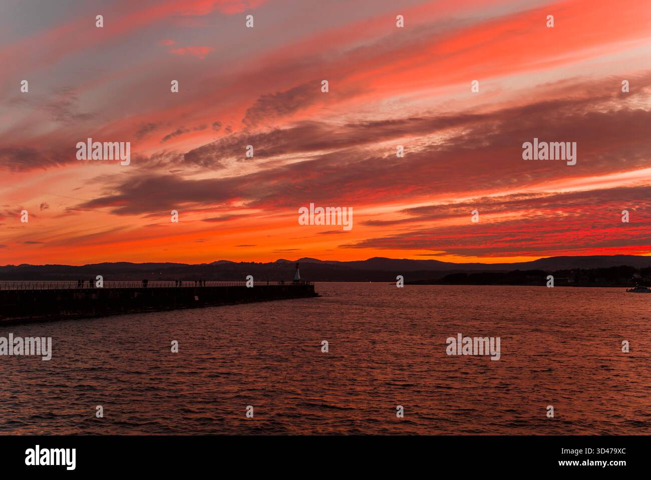 Un vibrante tramonto sulla costa del Pacifico, il cielo è saturo di colori vivaci, l'orizzonte è segnato da colline lontane. Foto Stock