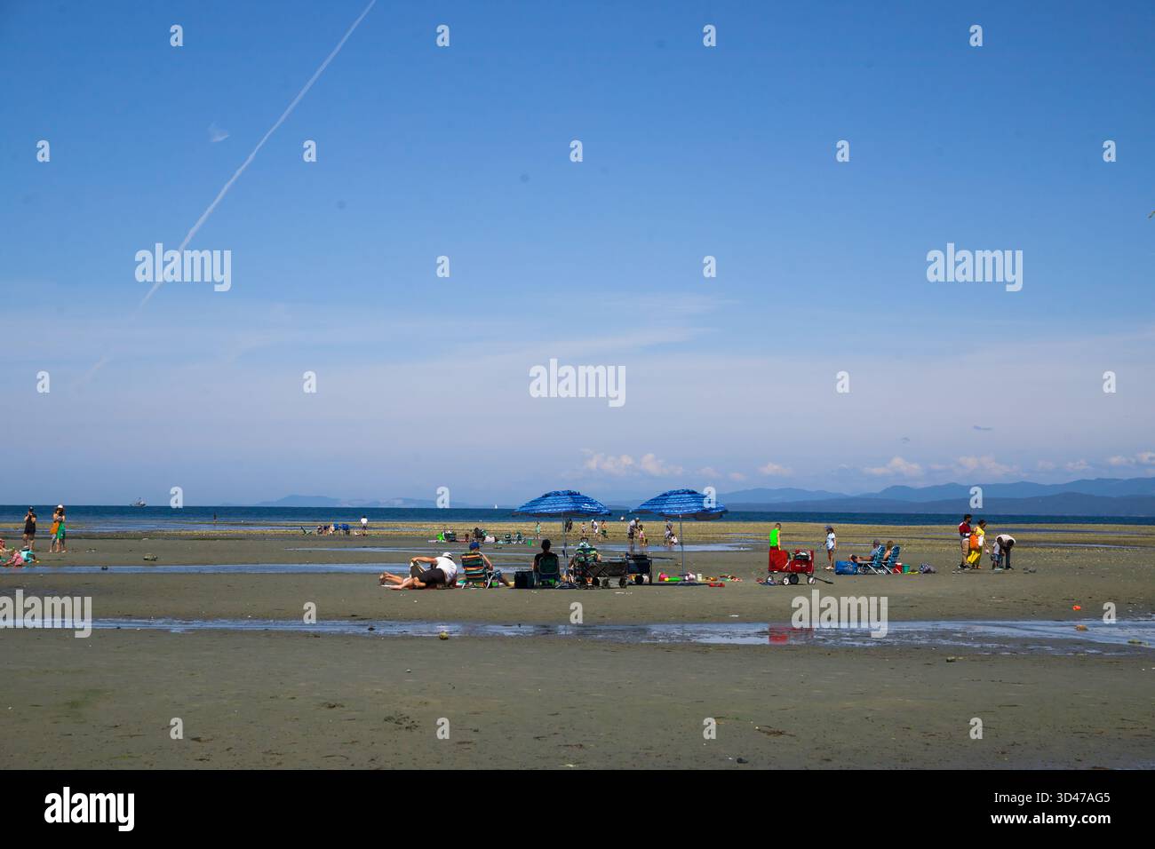 Parksville Beach, Isola di Vancouver - calme acque dell'Oceano Pacifico con la bassa marea. Persone che si rilassano con accessori da spiaggia e ombrelloni. Divertimento estivo, Foto Stock