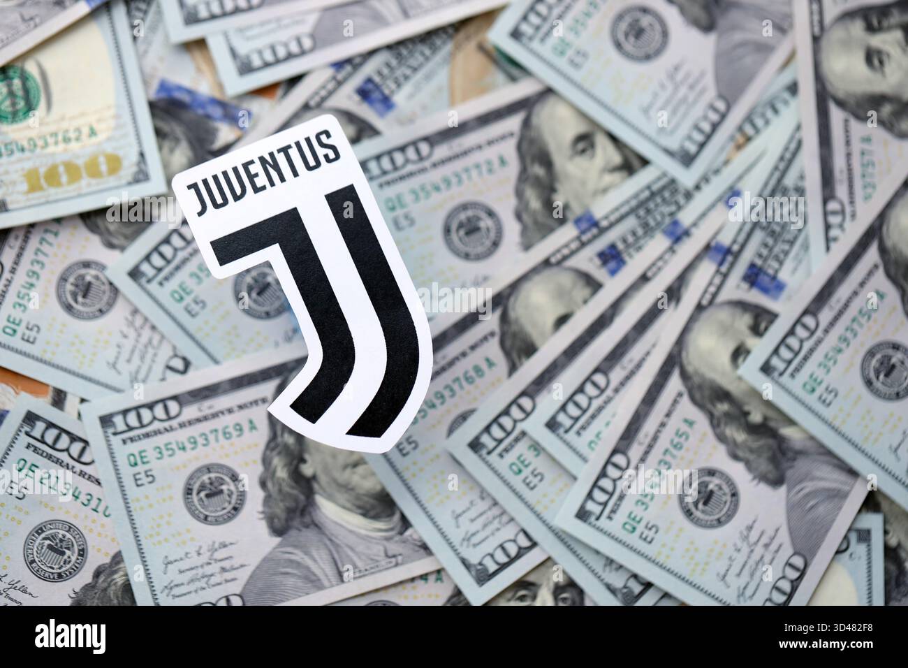 KIEV, UCRAINA - 23 FEBBRAIO 2025 il distintivo della squadra di calcio della Juventus FC si trova su una grande quantità di banconote da cento dollari Foto Stock