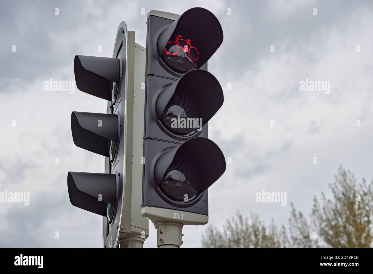 Primo piano di un moderno semaforo per biciclette, che mostra il segnale di stop rosso con il simbolo della bicicletta illuminata contro un cielo nuvoloso. Foto Stock