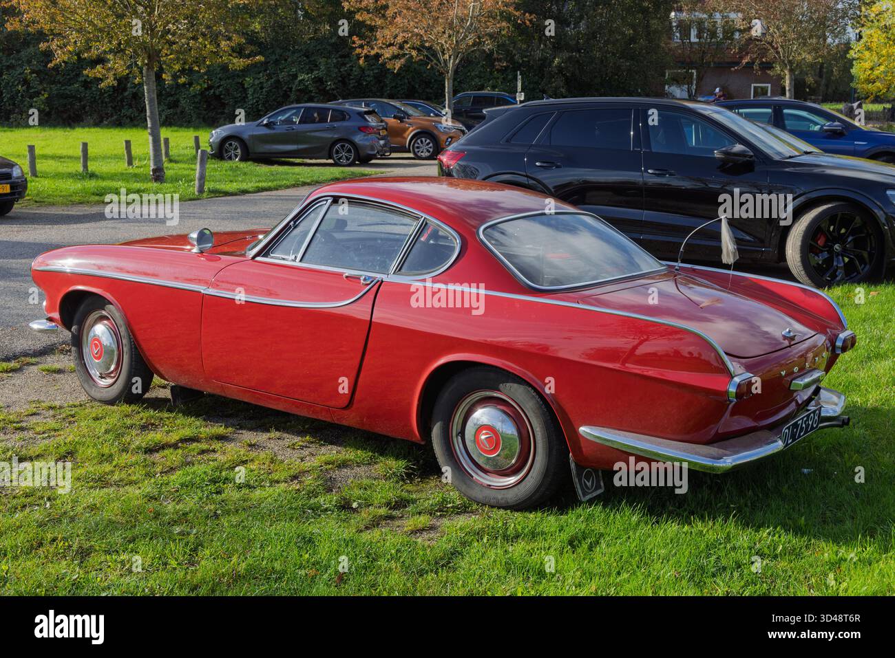 Vista posteriore di un'incredibile coupé Volvo P1800 rossa parcheggiata sull'erba, in contrasto con le auto moderne sullo sfondo. Utrecht Paesi Bassi, 2 novembre Foto Stock