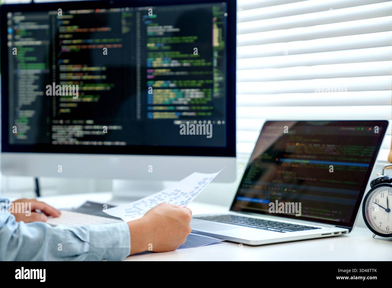 Programmatore che scrive codice programma con due monitor e lavora su un nuovo software o programmazione hacker che sviluppa applicazioni software in ufficio || modello rilasciato Foto Stock