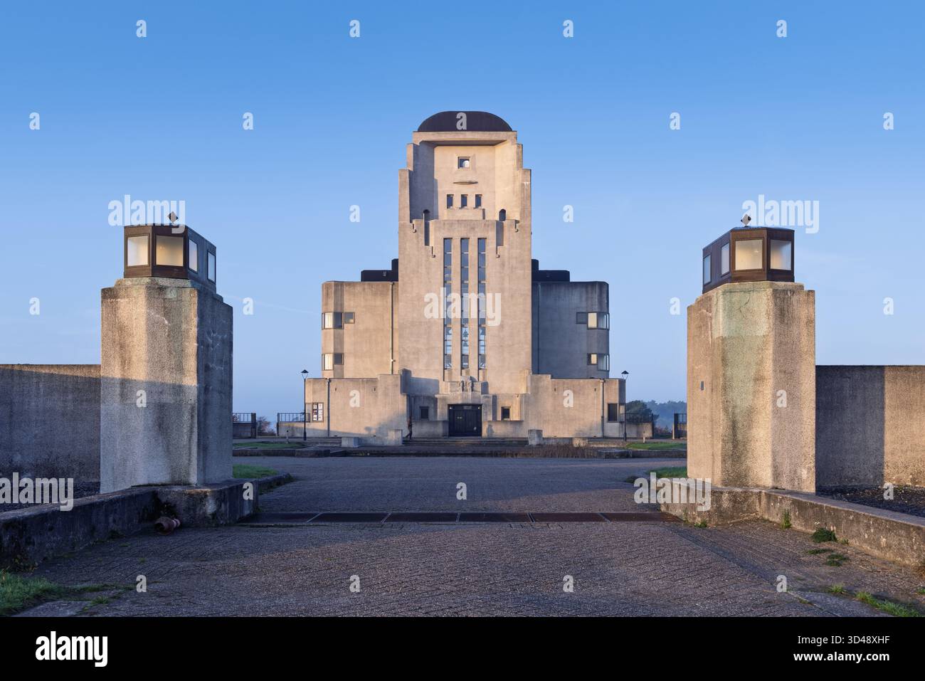 Vista frontale simmetrica del grande edificio principale Art Deco ("la Cattedrale") a radio Kootwijk, incorniciato da due pilastri di cemento alla luce del mattino. Foto Stock