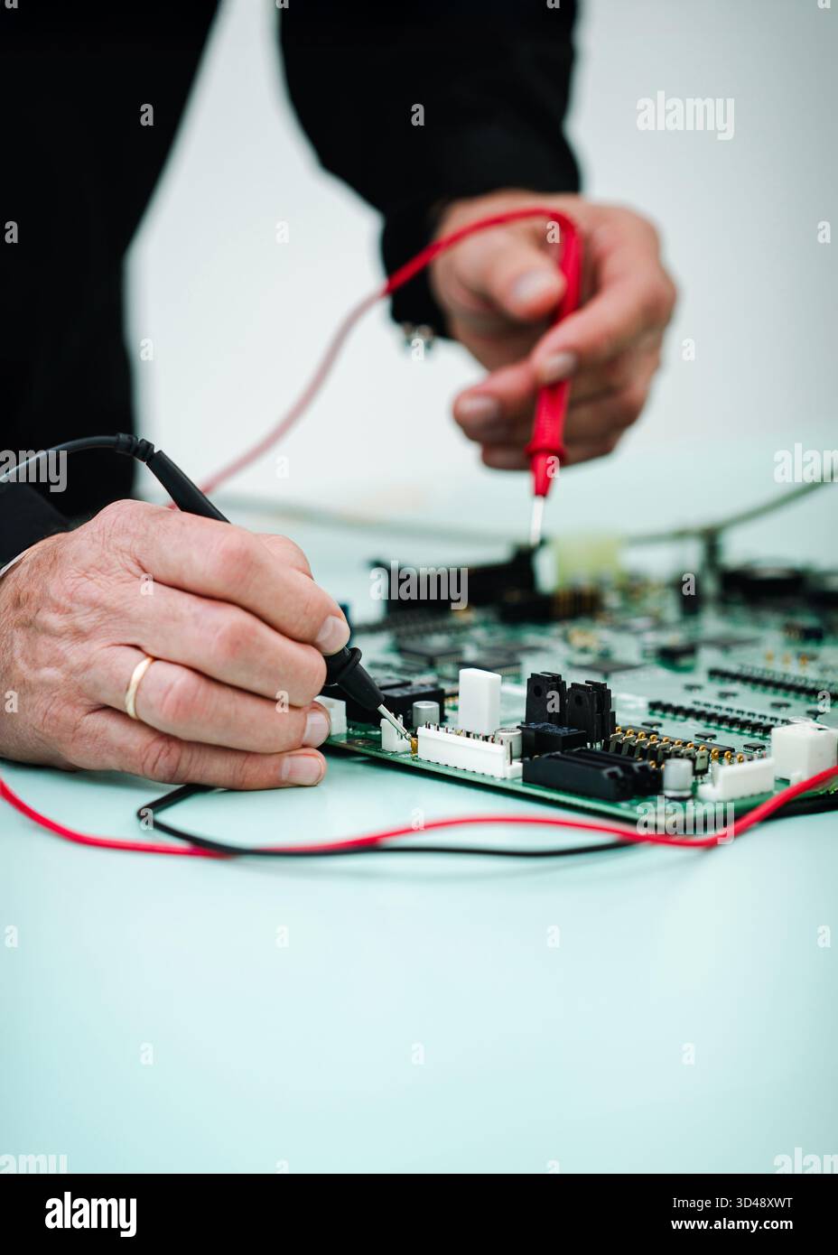 Il tecnico misura la tensione sulla scheda elettronica dell'apparecchiatura a raggi X utilizzando un multimetro digitale durante la manutenzione preventiva. Foto Stock