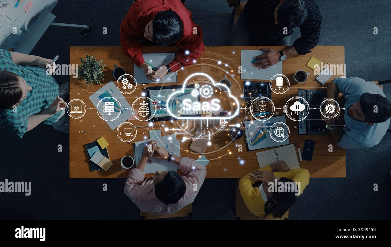Un team diversificato di professionisti collabora alle soluzioni SaaS in uno spazio di lavoro moderno. Le icone digitali illustrano i concetti di cloud computing e. Foto Stock