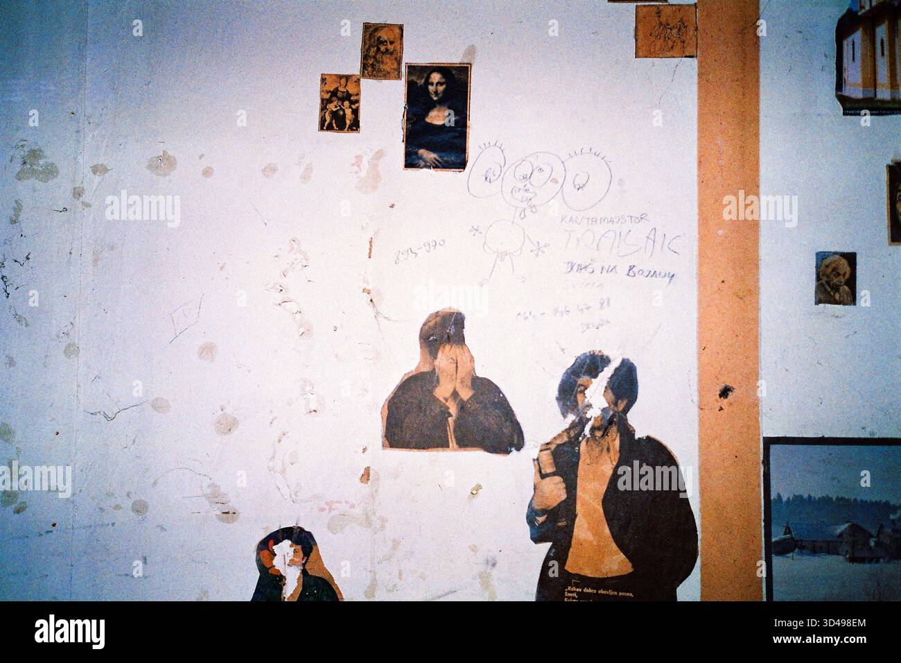 Parete bianca del magazzino abbandonato con ragnatele, vecchi poster, tra cui annunci multimediali e Monna Lisa, foto flash analogica con texture grintosa. Foto Stock