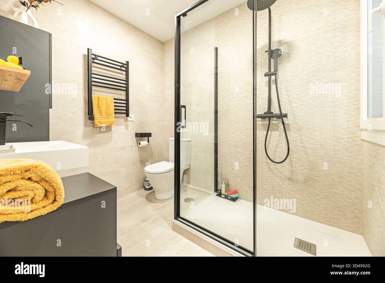 Una ristrutturazione pratica di un bagno compatto con cabina doccia e sistema di drenaggio lineare, che incorpora nicchie di stoccaggio incorporate e fau nascosta Foto Stock