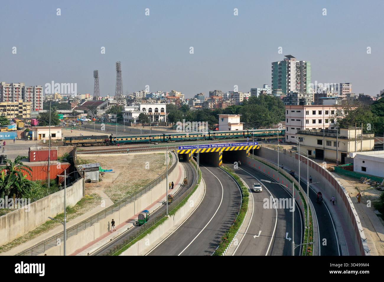Dacca, Bangladesh - 8 novembre 2025: Il traffico è iniziato sul sottopassaggio a sei corsie costruito al TT Para di Dacca. I treni stanno andando sopra e i veicoli ar Foto Stock