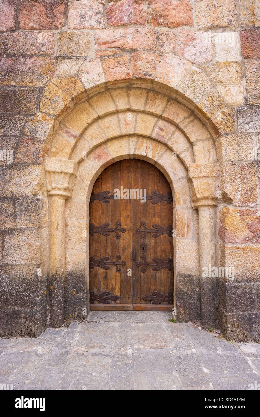 L'antica arcata in pietra incornicia questa storica porta in legno con cerniere in ferro Foto Stock