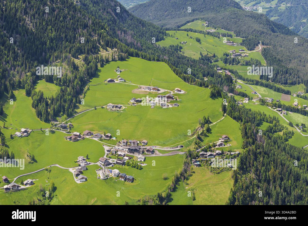 Vista aerea panoramica dell'idilliaco villaggio alpino circondato da lussureggianti colline verdi vicino alla Valle di Funes alle Dolomiti, Italia Foto Stock