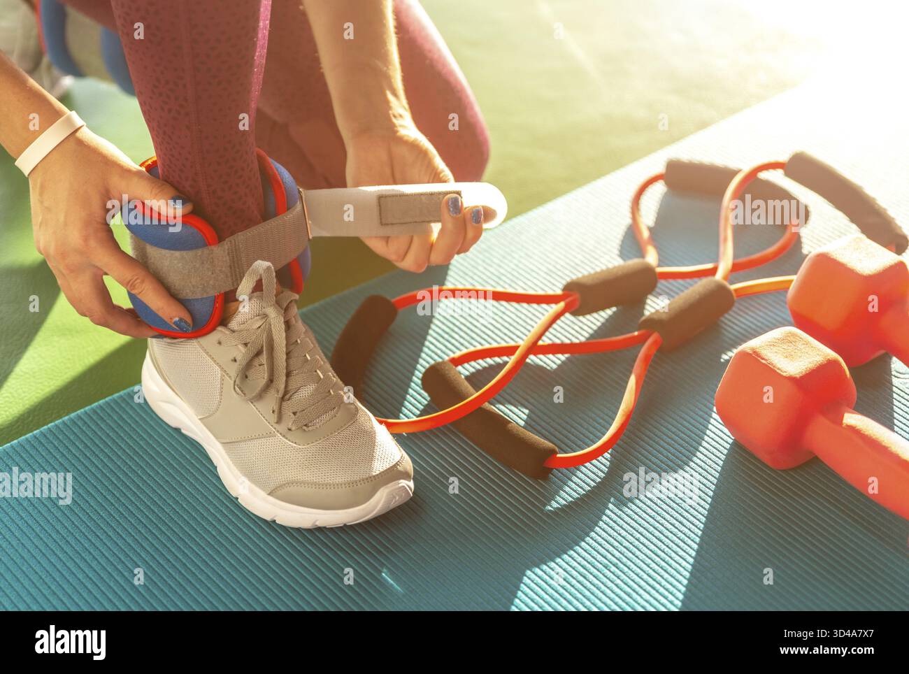 Donna mettendo sulla caviglia wights prima che lei inizia un allenamento in palestra fitness e salute Foto Stock