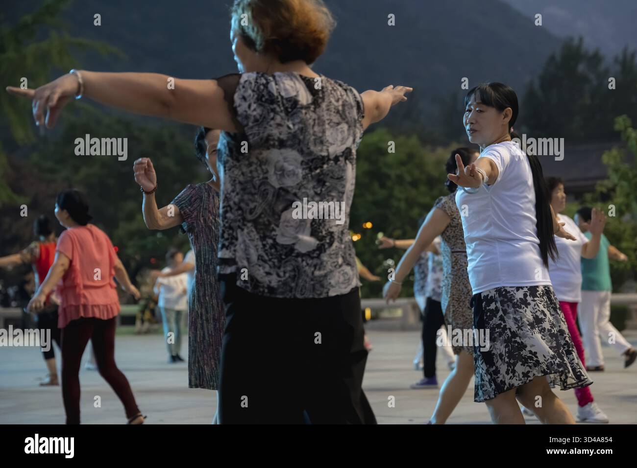 Huashan, Cina - agosto 2019 : gruppo di donne cinesi che ballano nella piazza aperta ai piedi del monte Huashan al crepuscolo, nella provincia di Shaanxi Foto Stock