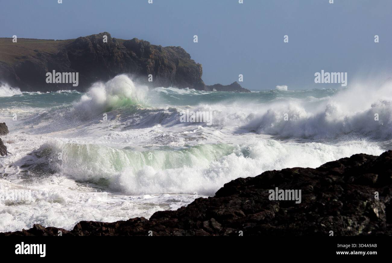 Mare turbolento e bollente con grandi onde a Kynance Cove sulla Penisola di Lizard, in Cornovaglia. Rocce frastagliate sulla spiaggia in primo piano. Foto Stock