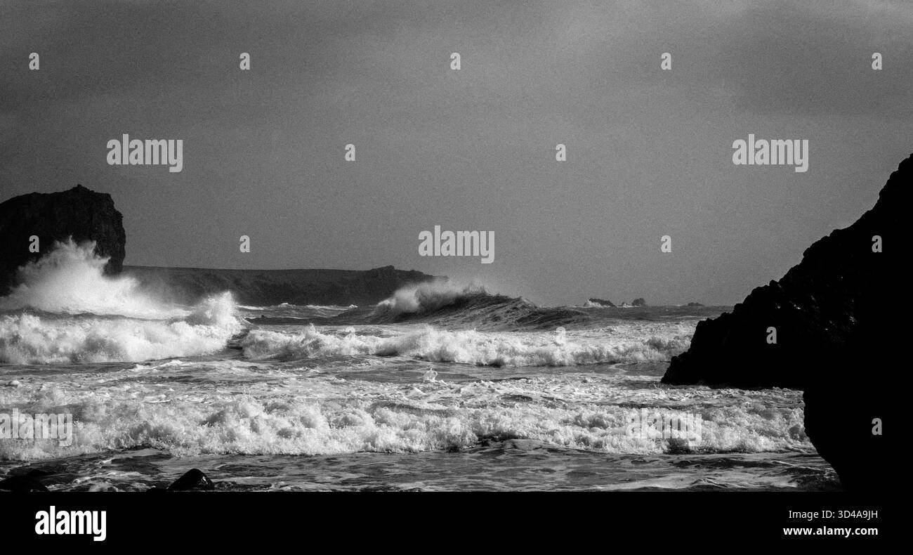 Rompere le onde e fare surf dalla spiaggia di Kynance Cove sulla penisola di Lizard, in Cornovaglia. Si chiama Lion Rock a sinistra. Dopo una tempesta Foto Stock