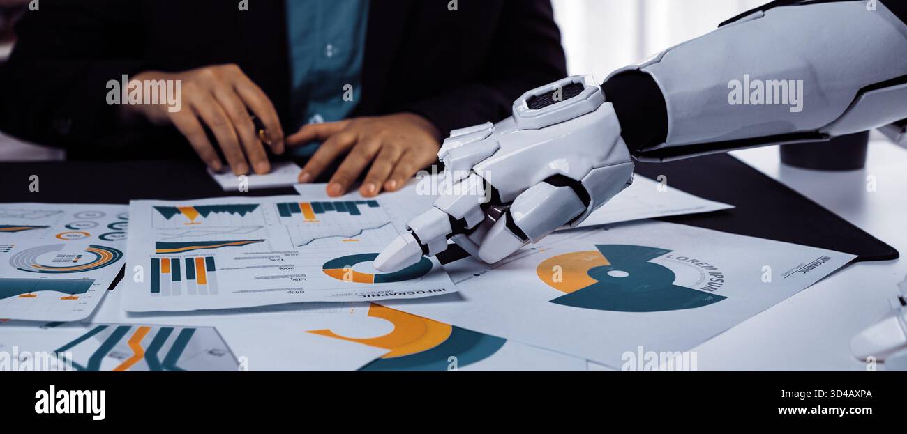 Un robot umanoide si concentra sui documenti finanziari con grafici colorati mentre un professionista aziendale gesta. Questa scena cattura l'innovazione Foto Stock