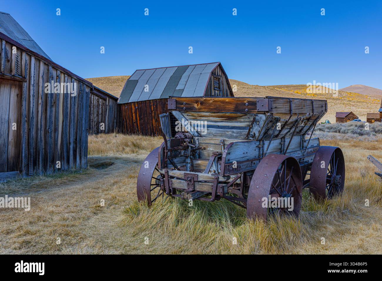 Vecchio carro in legno e fienili intemprati nella città fantasma di Bodie Foto Stock