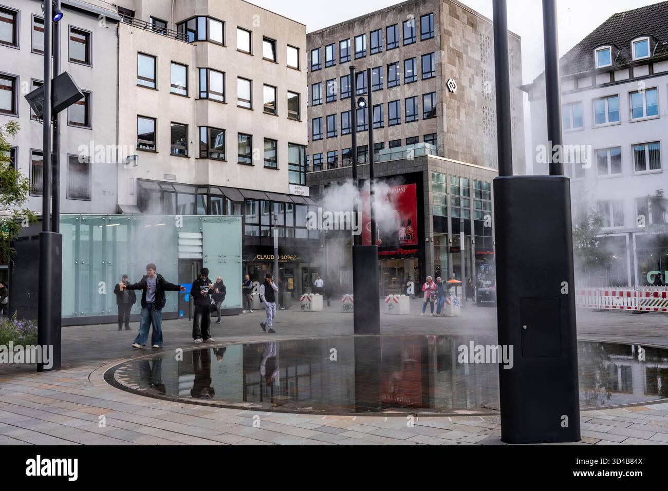 Impianto idrico digitale, installazione di acqua Blue Cloud su Husemannplatz nel centro di Bochum. La nebbia d'acqua viene spruzzata da quattro montanti metallici, che, in co Foto Stock
