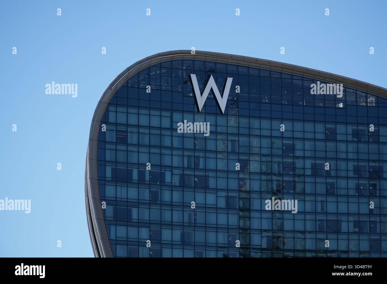 Il W Sydney, un hotel di lusso a Sydney, Australia, presenta la sua moderna facciata in vetro curvo e l'iconico logo "W" sotto un cielo azzurro. Foto Stock