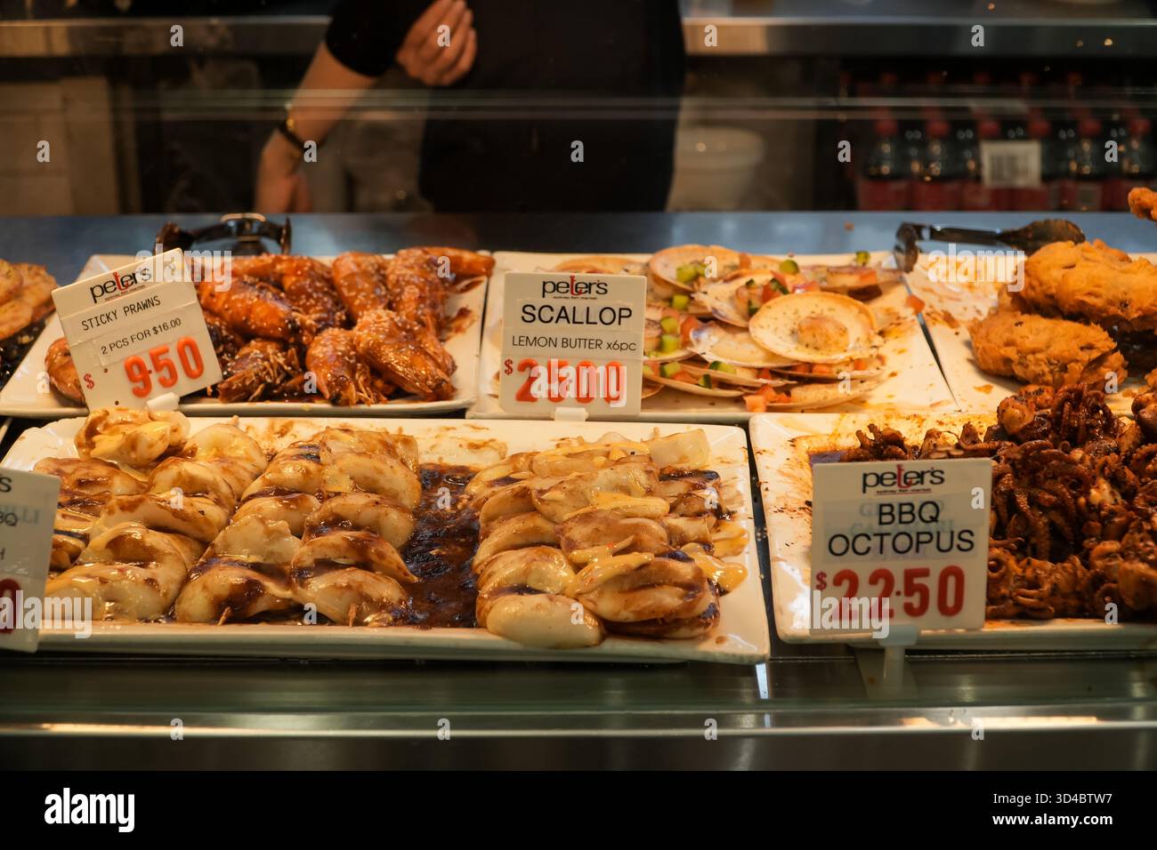 Il mercato del pesce di Sydney offre una varietà di pesce cucinato come gamberi appiccicosi, capesante al burro di limone e polpo barbecue, a prezzi visibili, pronti per Foto Stock