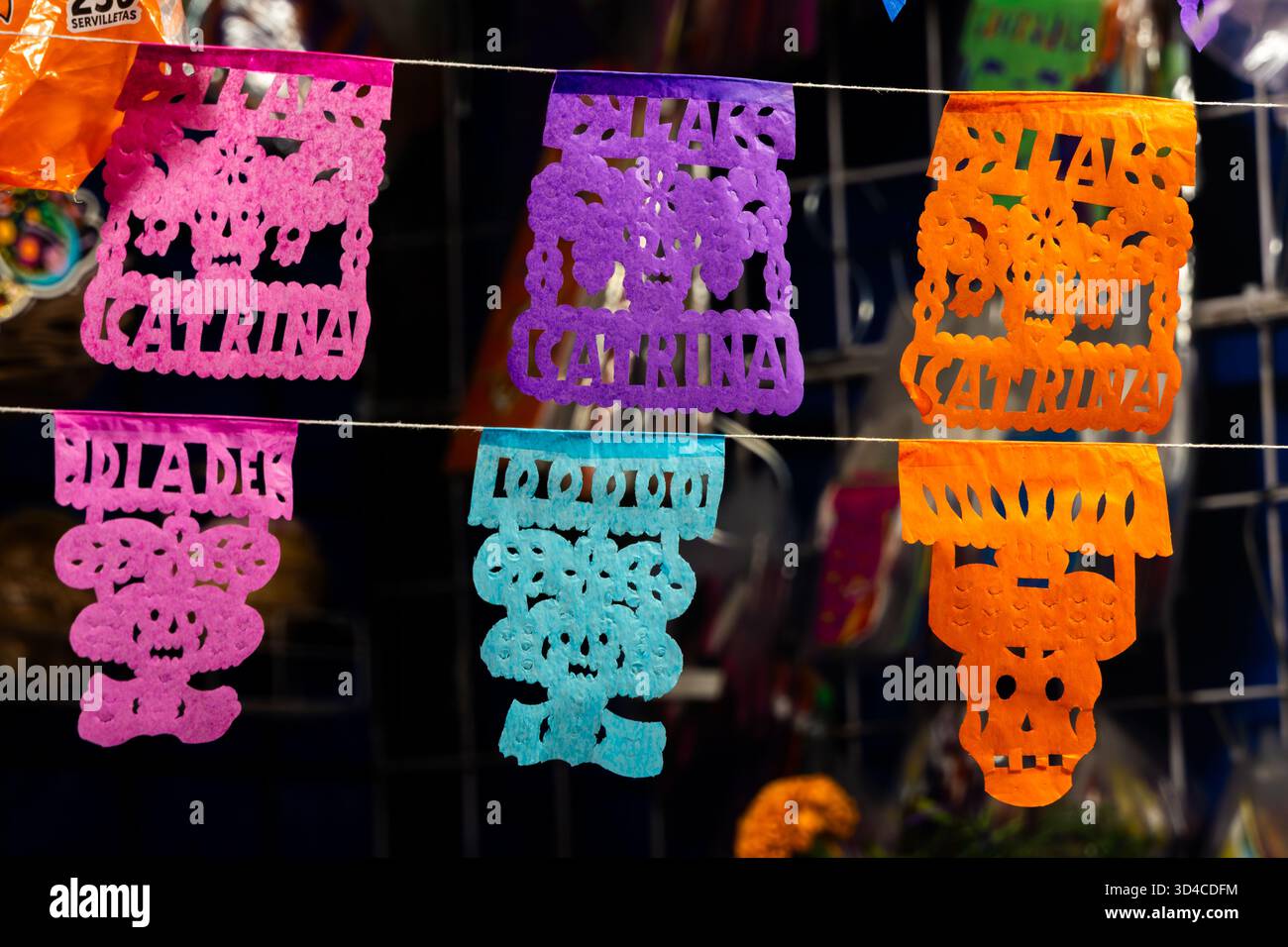 Una fila di bandiere di carta colorata con i nomi delle persone sopra di loro. Le bandiere sono appese su un cavo. Giorno messicano della tradizione dei morti, offerte, cibo, c Foto Stock