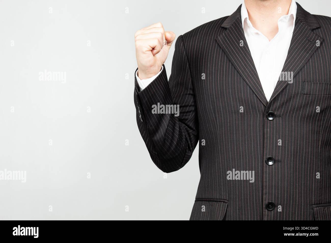 Primo piano di un uomo d'affari con la tuta sul lato destro dello schermo che stringe il pugno in aria per esprimere soddisfazione Foto Stock