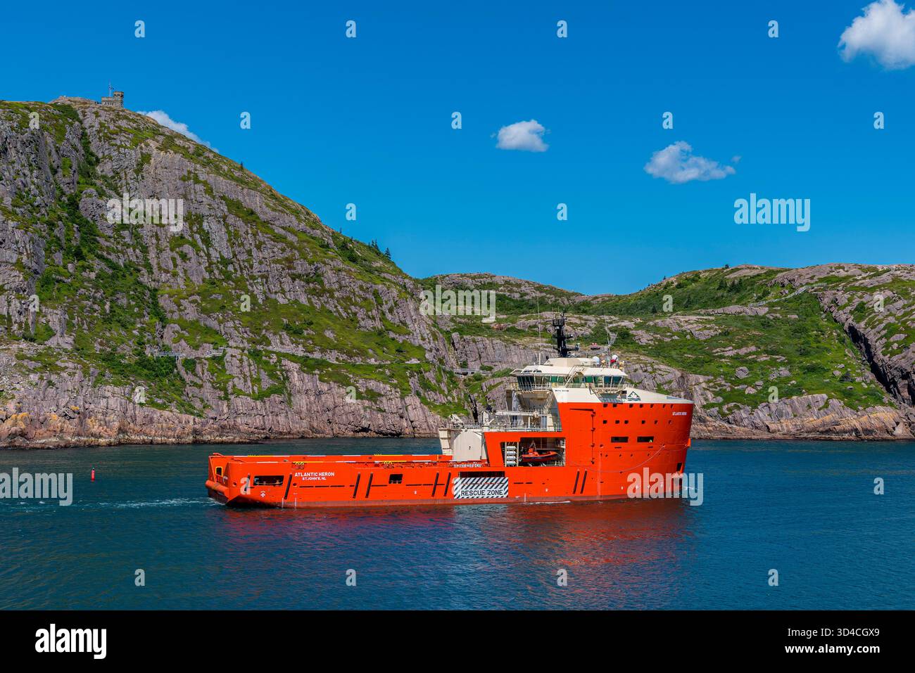 St. Johns, NL, Canada- 9 agosto 2024: Nave di rifornimento offshore Atlantic Heron che lascia il porto di St Johns a Terranova con Cabot Tower i. Foto Stock