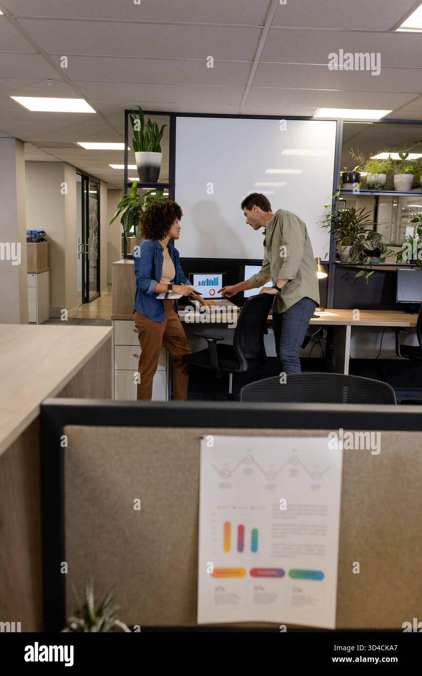 Revisione di diversi colleghi che analizzano grafici a barre e grafici a torta in ufficio, con tablet e notebook Foto Stock