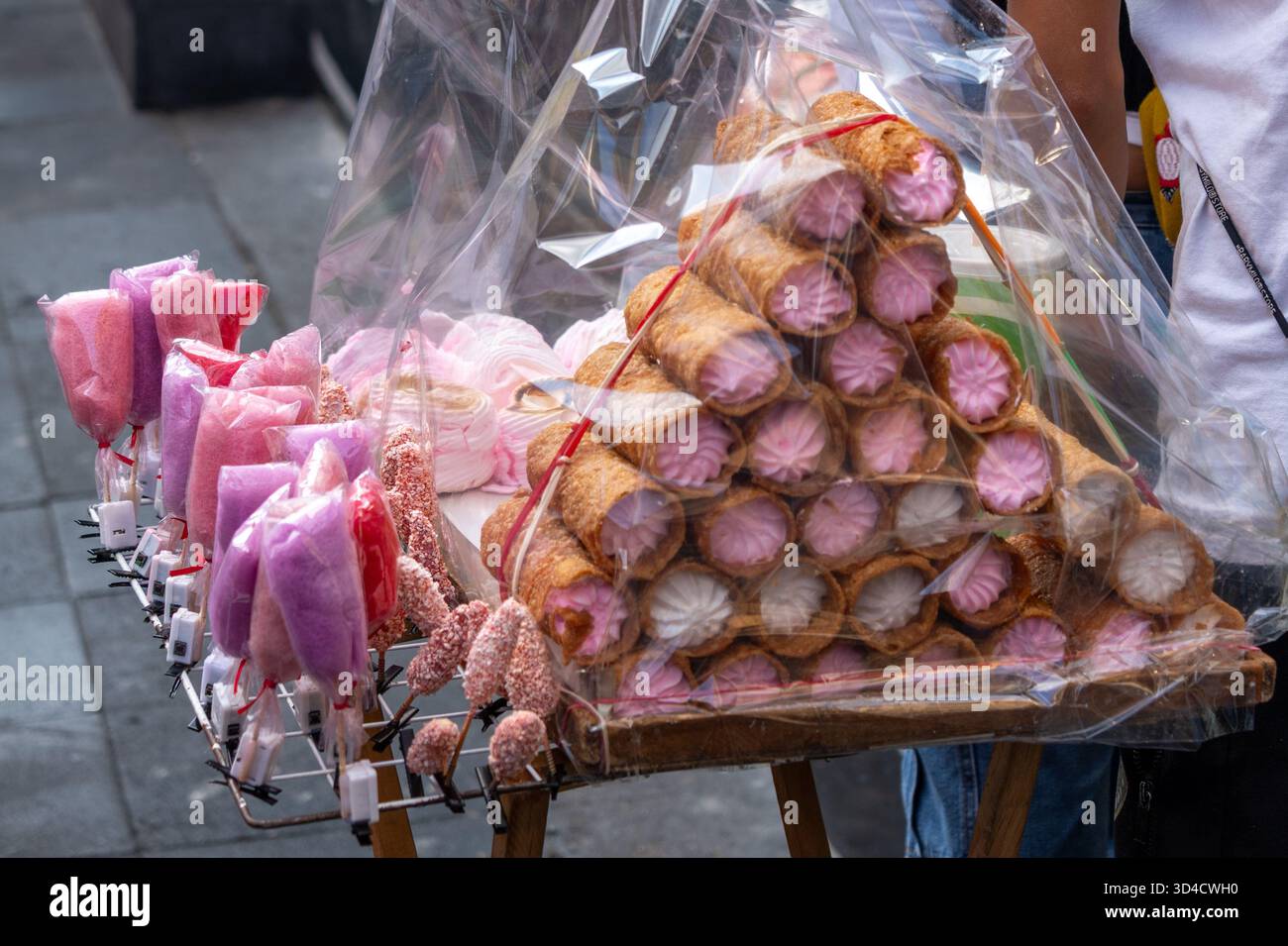 Un venditore sta vendendo una varietà di pasticcini rosa in sacchetti di plastica, con una persona in piedi dietro la ta. Giorno messicano della tradizione dei morti, offerte, per Foto Stock