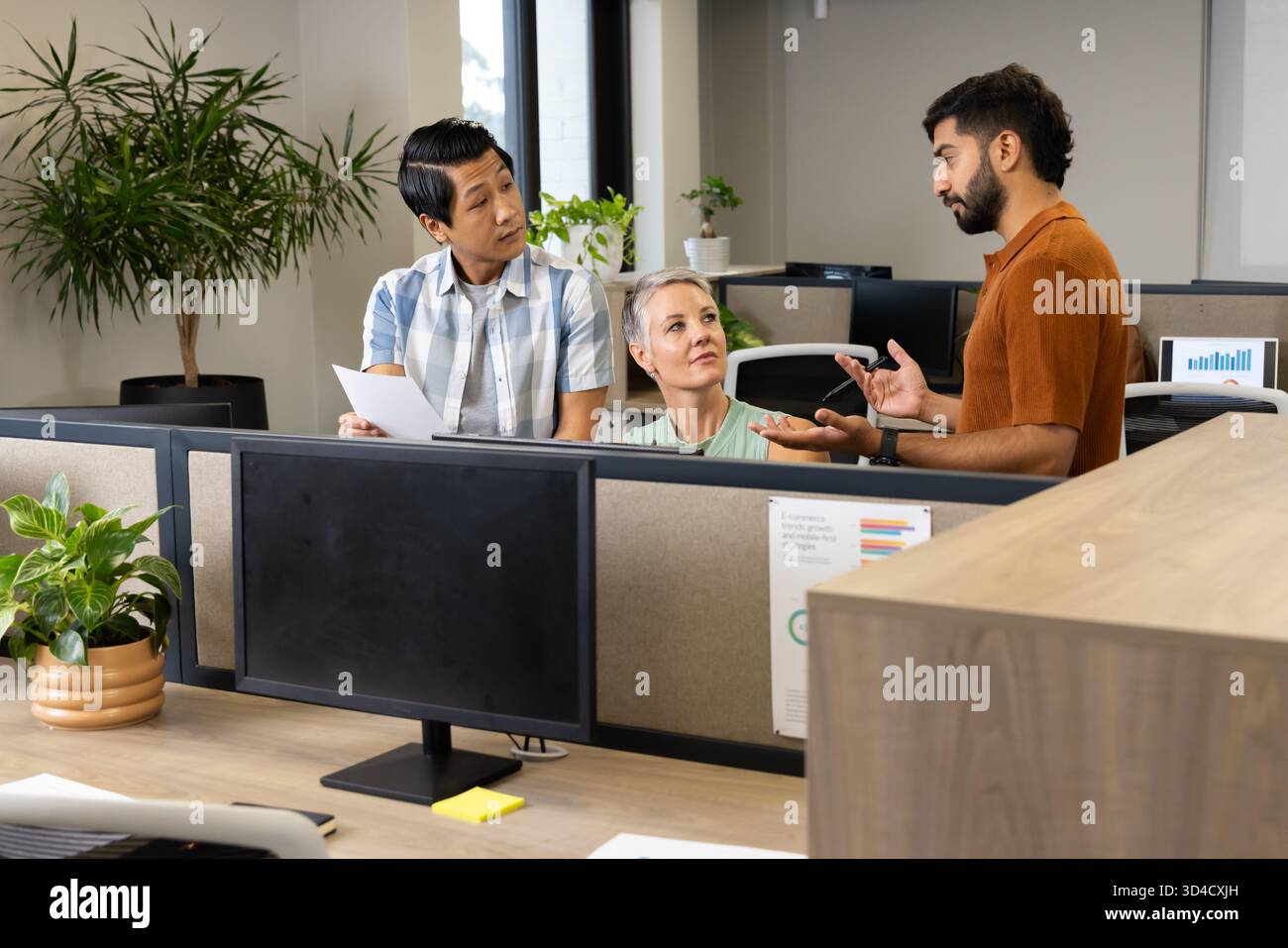 Collaborazione con colleghi diversi che scambiano idee alla scrivania open space, con grafici e telefono Foto Stock