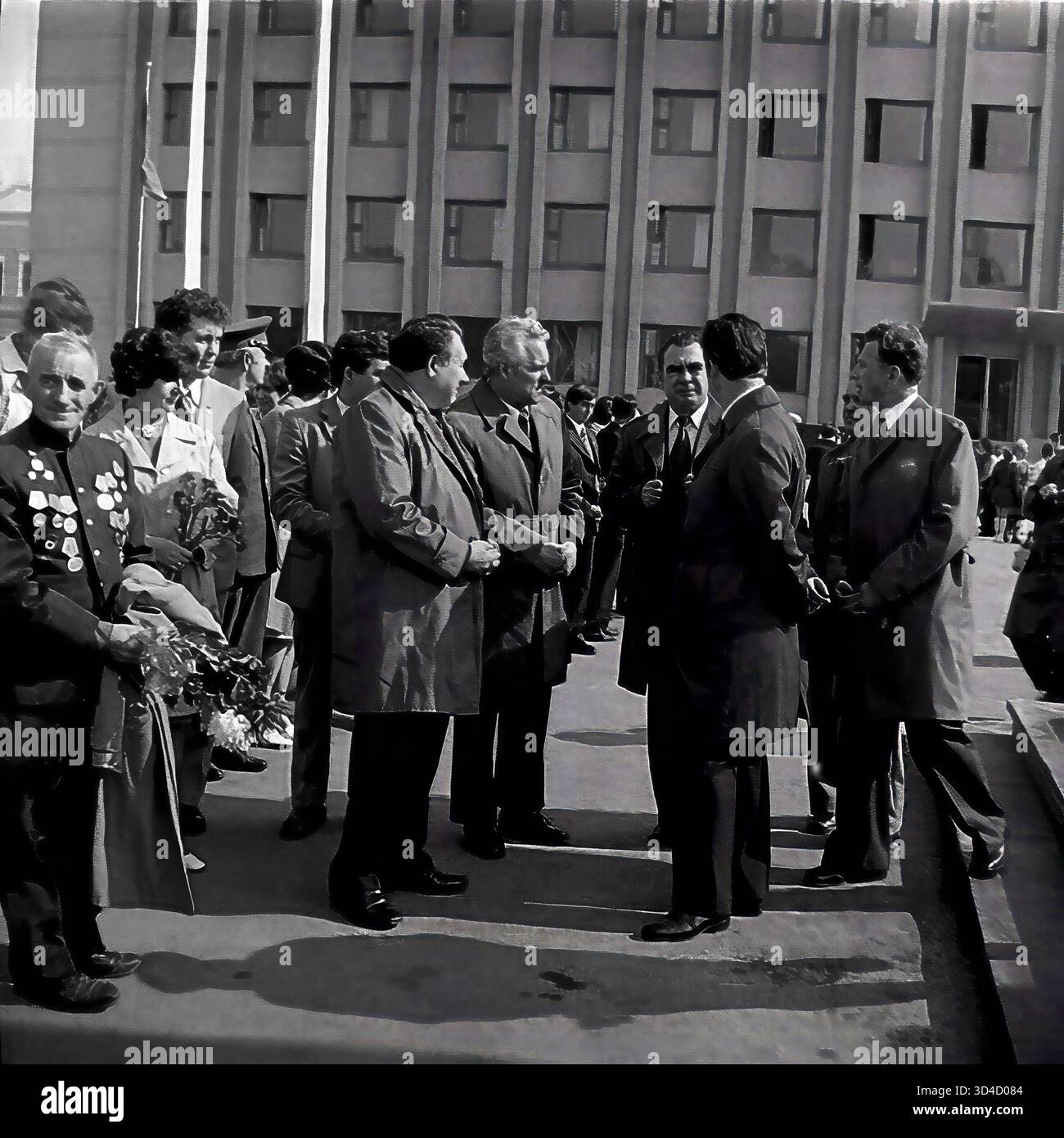 Foto d'archivio degli anni '1980 mostra la celebrazione del 7 novembre (anniversario della rivoluzione d'ottobre) a Sloviansk, RSS Ucraina. In Piazza della Rivoluzione d'ottobre (ora Piazza Soborna), veterani e funzionari della città si riuniscono. Un veterano della seconda guerra mondiale (a sinistra), il suo petto coperto di medaglie e un gruppo di leader di partito parlano. L'edificio Gorkom (Comitato cittadino) è sullo sfondo. Questo cattura l'incontro ufficiale per la festa sovietica. Questo è un momento di vita pubblica nel pacifico Donbas prima della guerra. Foto Stock