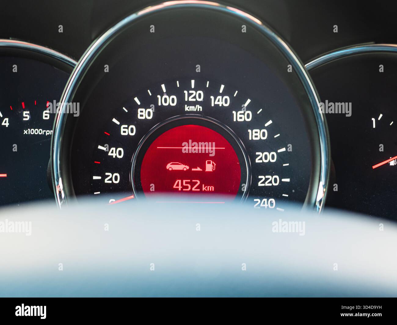 Il cruscotto mostra una vista ravvicinata del tachimetro e dell'indicatore di livello del carburante di un'auto moderna, evidenziando la velocità corrente e il carburante rimanente in chilometri. Foto Stock