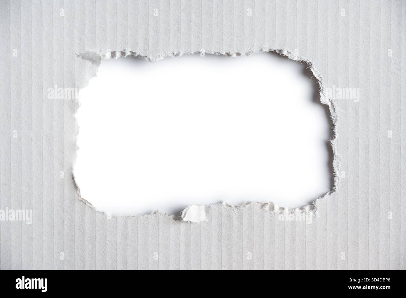 Carta corrugata bianca con un foro con bordi strappati. Foto Stock