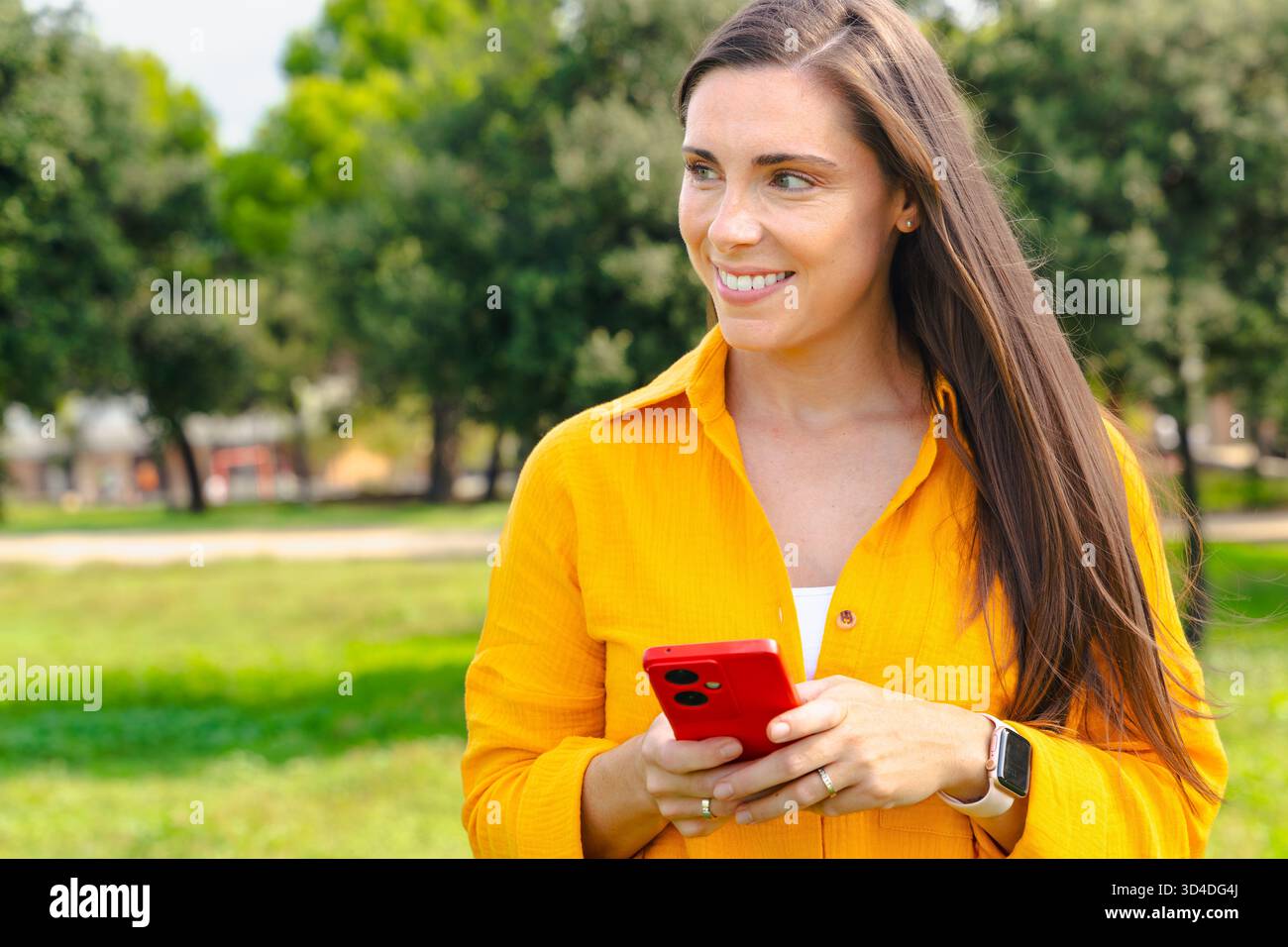 Giovane donna che tiene lo smartphone all'aperto sorridente con spazio fotocopie naturale Foto Stock