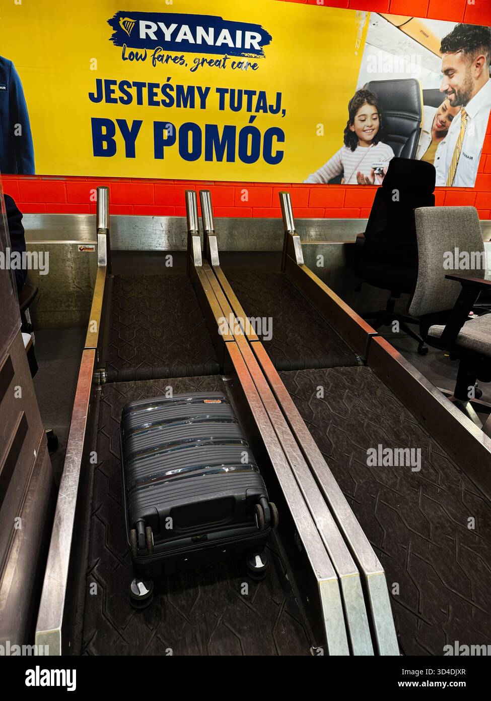 Nowy Dwor Mazowiecki, Polonia - 22 ottobre 2025: Scena di viaggio con una pubblicità Ryanair come valigia poggia sulle cinture bagagli all'aeroporto. Foto Stock