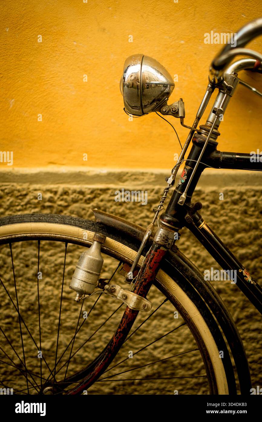Una bicicletta si appoggia contro un muro giallo a Buonconvento, in Italia. Foto Stock