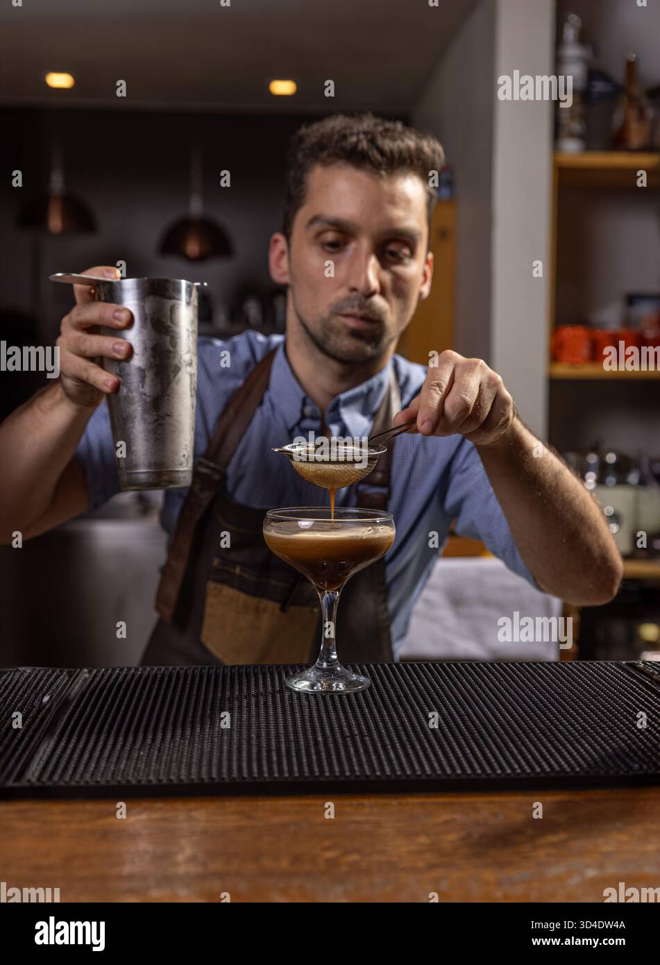 Barman versare con cura un ingrediente in un bicchiere da cocktail Foto Stock
