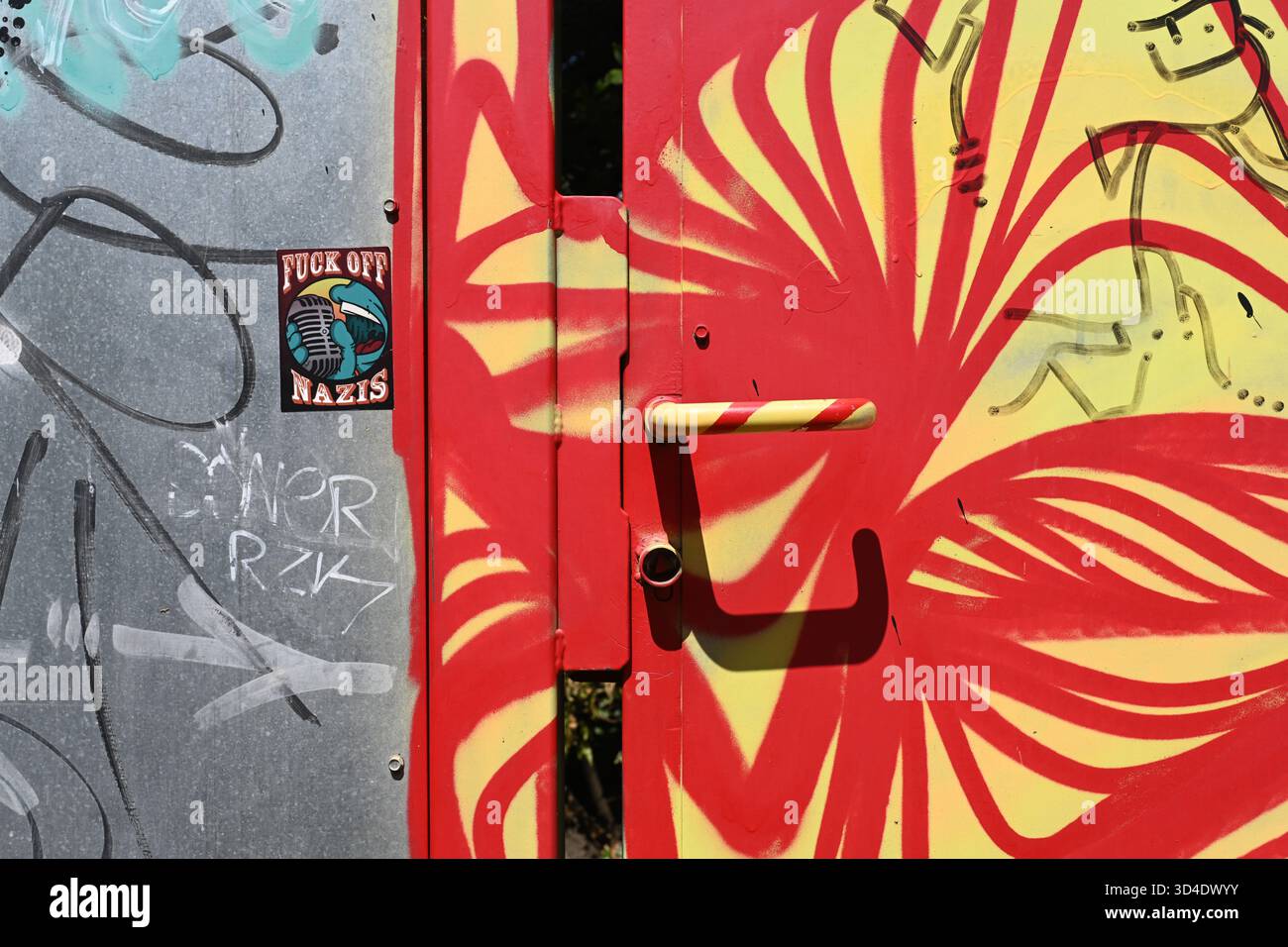 Porta di sicurezza in metallo o ingresso decorato in graffiti astratti modernisti con colorate maniglie rosse e gialle Foto Stock