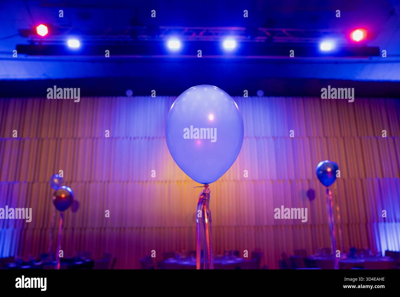Focalizzatevi su un elegante palloncino blu circondato da luci soffuse nello spazio banchetti, composizione artistica di decorazioni festive, armonia dei colori e feste moderne Foto Stock