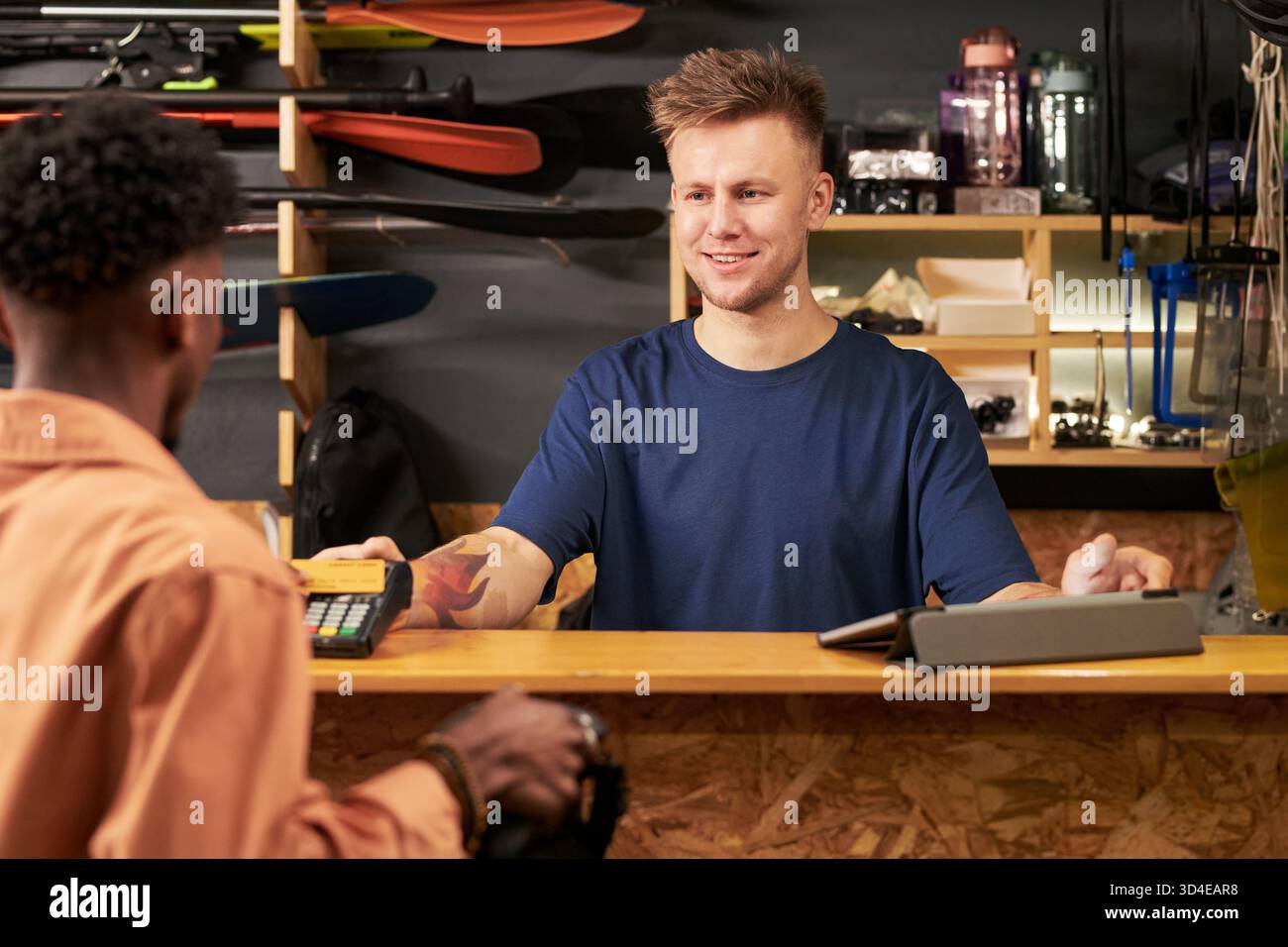 Young Man assiste Black Young Man al banco cassa Foto Stock