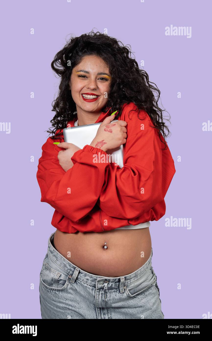 Allegra donna gen z che tiene in mano un dispositivo, esprimendo positività e gioia del corpo Foto Stock