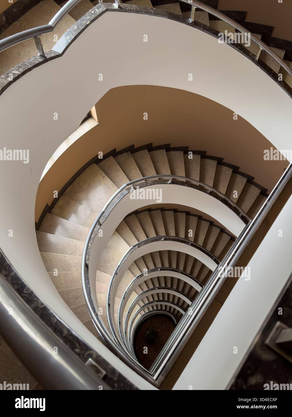 Vista dall'alto della tortuosa scalinata a spirale con ringhiere in metallo e gradini in pietra che formano uno spettacolare schema architettonico Foto Stock