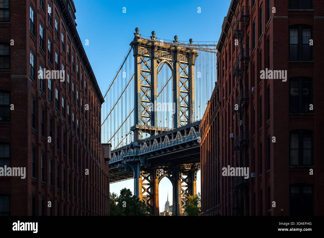 Il maestoso ponte di Manhattan visto dal livello della strada nel quartiere DUMBO di Brooklyn, incorniciato da classici edifici in mattoni rossi. Foto Stock
