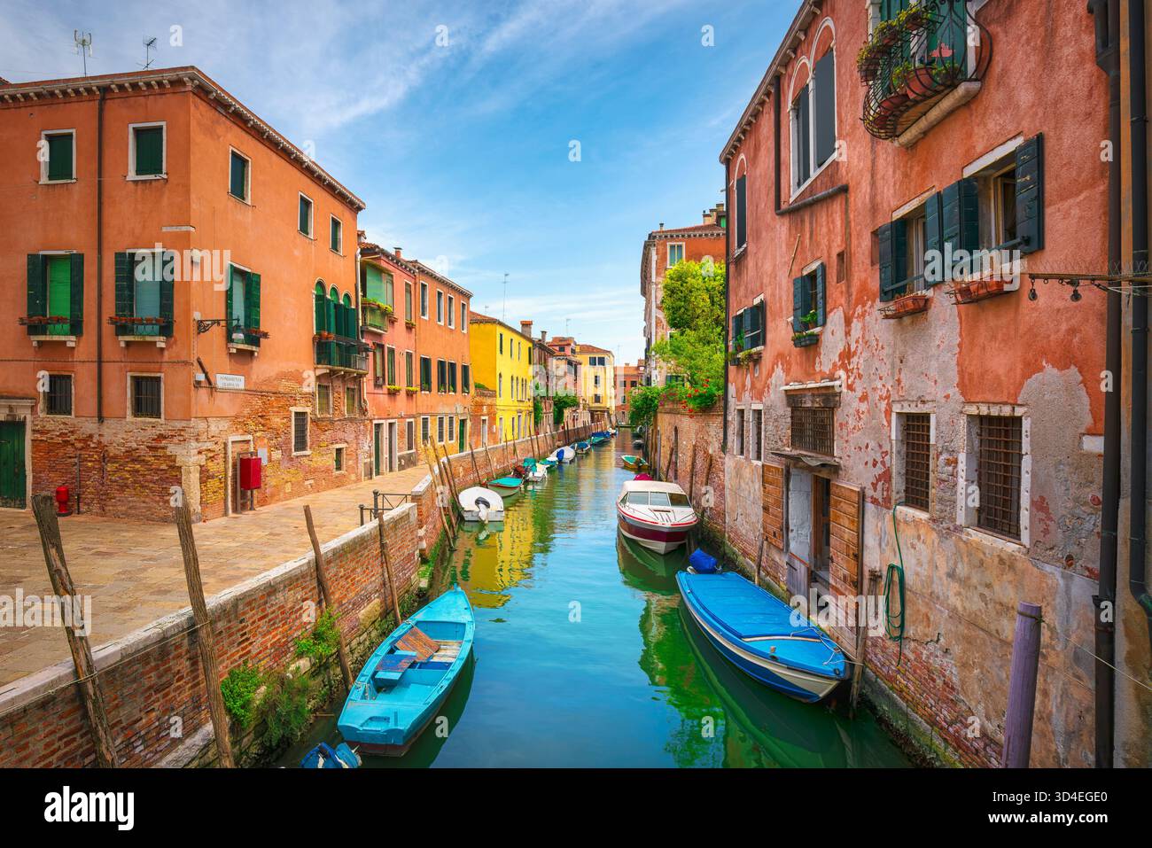 Affascinante e stretto canale di Venezia, caratterizzato da barche ancorate ed edifici colorati su entrambi i lati. Cielo azzurro luminoso sopra la fondamenta Trapolin creano Foto Stock
