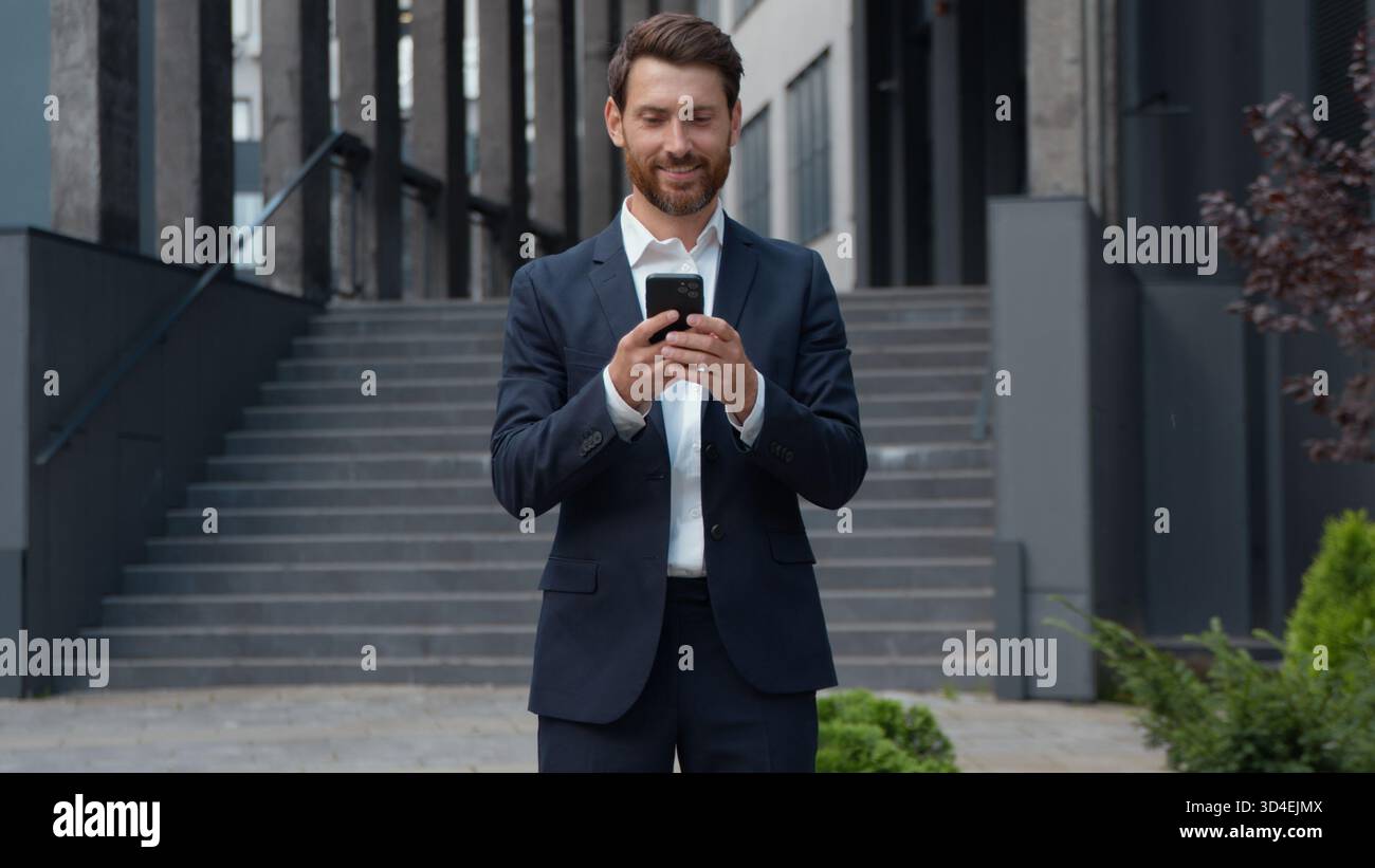 Uomo d'affari maturo di successo caucasico in città uomo d'affari con il telefono che tiene lo smartphone utilizzando l'applicazione mobile che controlla l'e-mail maschio adulto Foto Stock
