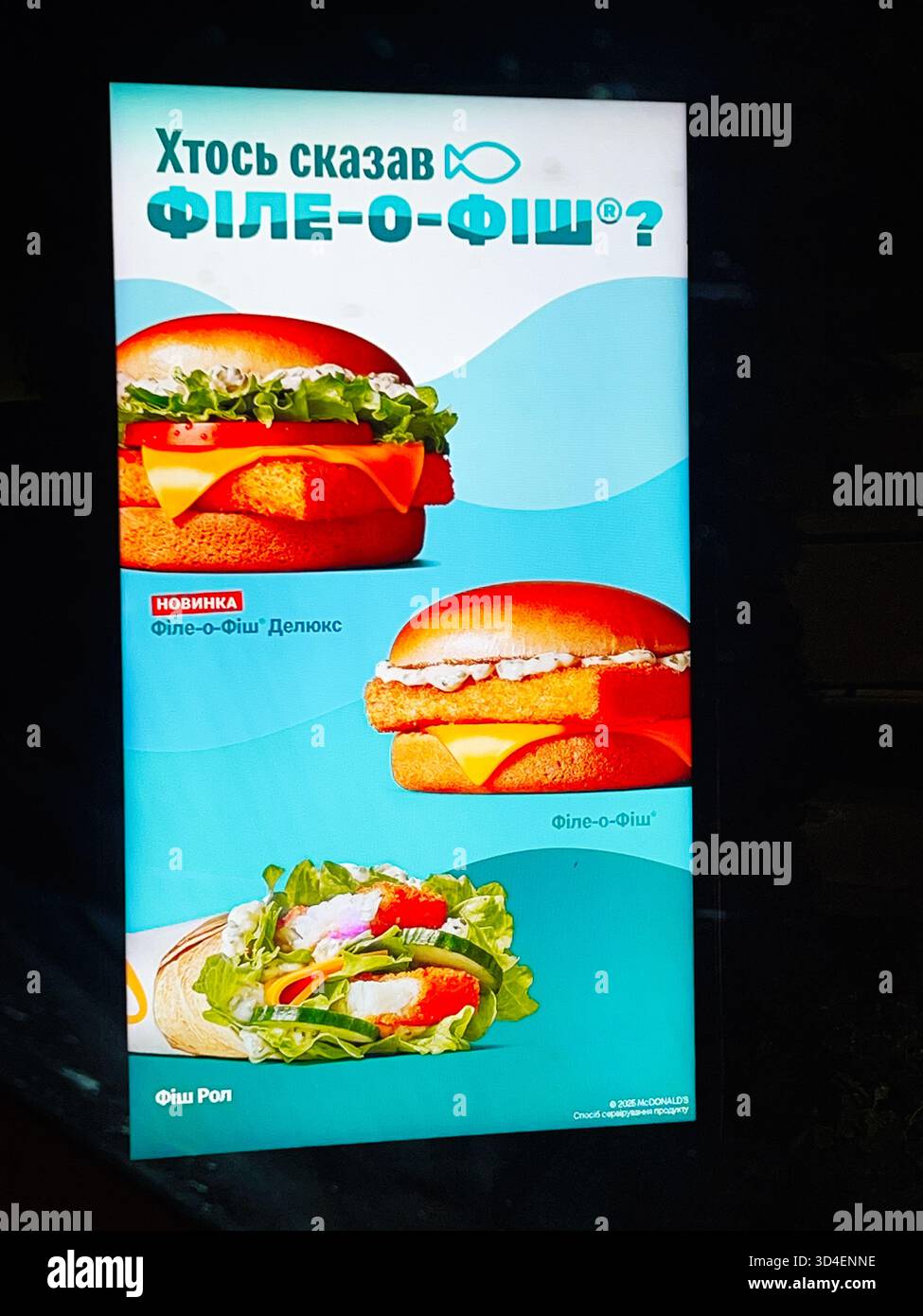 Kiev, Ucraina - 10 novembre 2025: Cartello fast food di Bright McDonald's che mostra hamburger di pesce, involtini e verdure fresche su sfondo blu. Foto Stock