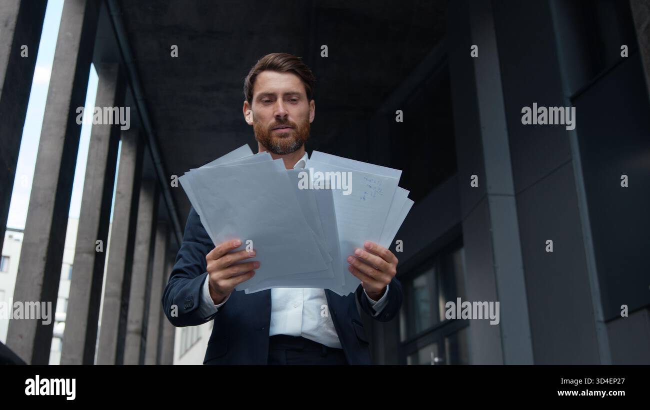 Uomo d'affari caucasico maturo di successo con documenti in mano in città occupato con un contratto di lavoro dirigente d'affari di mezza età Foto Stock