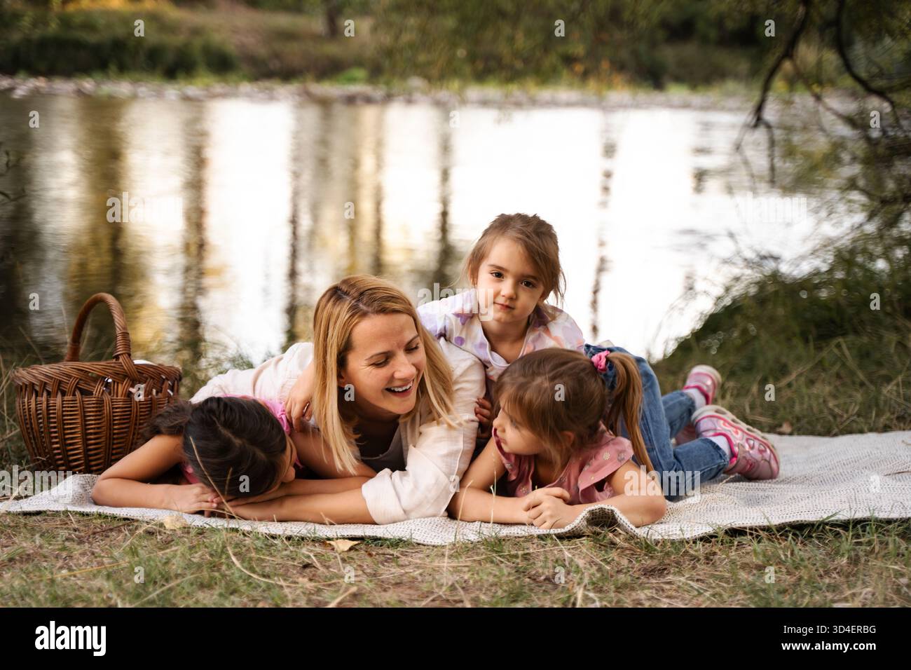 Madre e figlie si divertono ad un picnic sul fiume Foto Stock