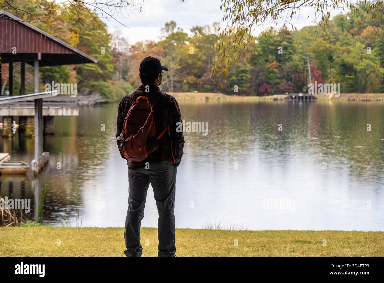 Uomo che si gode la vista del lago Trahlyta con il fogliame autunnale circostante al Vogel State Park, vicino a Blairsville, Georgia. (USA) Foto Stock